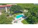 Aerial view of a community pool surrounded by lush greenery and a multi-story building at 4800 Gulf Of Mexico Dr # 204, Longboat Key, FL 34228