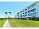 Exterior view of condo building with manicured lawn and carports at 4800 Gulf Of Mexico Dr # 204, Longboat Key, FL 34228