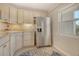 Well-lit kitchen featuring bright cabinets, stainless steel refrigerator, and tiled floor at 4800 Gulf Of Mexico Dr # 204, Longboat Key, FL 34228