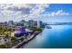An aerial view features a coastal city skyline along a bay under a bright blue sky with puffy white clouds at 50 Central Ave # 17Phd, Sarasota, FL 34236