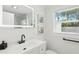 Bright bathroom features a modern vanity, black fixtures, framed art, and a window view with palm trees at 578-580 Companion Way, Longboat Key, FL 34228