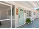 Inviting exterior of a home featuring a teal door, white gravel landscaping, and a screened porch at 578-580 Companion Way, Longboat Key, FL 34228