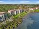 Aerial view of waterfront condos featuring well-manicured lawns, mature palm trees, and beachfront access at 6470 Mourning Dove Dr # 201, Bradenton, FL 34210