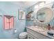 Light and airy bathroom with blue walls, granite vanity, and a round mirror providing a coastal feel at 6470 Mourning Dove Dr # 201, Bradenton, FL 34210