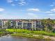 Stunning waterfront condo building with balconies, manicured lawn, palm trees and private beach access at 6470 Mourning Dove Dr # 201, Bradenton, FL 34210