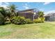Expansive backyard showcasing a well-kept lawn, tropical foliage, and screened lanai at 6519 43Rd E Ct, Sarasota, FL 34243