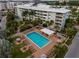Aerial view showcasing the pool and multi-story condo buildings surrounded by lush landscaping and mature trees at 6610 Midnight Pass Rd # 11, Sarasota, FL 34242