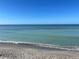 Tranquil beach scene with calm, light blue water gently lapping the sandy shore under a clear blue sky at 6610 Midnight Pass Rd # 11, Sarasota, FL 34242