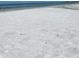 Expansive view of a bright white sand beach with gentle waves meeting the shore on a sunny day at 6610 Midnight Pass Rd # 11, Sarasota, FL 34242