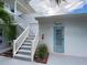 Charming exterior view with stairs leading to the unit, highlighted by a blue door and tropical landscaping at 6610 Midnight Pass Rd # 11, Sarasota, FL 34242