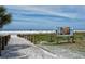 Scenic entrance to Siesta Beach with white sand, grassy dunes, and beachgoers in the distance at 6610 Midnight Pass Rd # 11, Sarasota, FL 34242