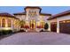 Beautiful home with an illuminated paver driveway, arched windows, and mature landscaping at 6819 Dominion Ln, Lakewood Ranch, FL 34202