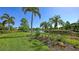 Serene golf course view showcases a pond, palm trees, manicured landscaping, and clear blue sky at 6819 Dominion Ln, Lakewood Ranch, FL 34202