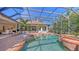 Beautiful screened-in pool with spa and brick surround, complemented by lush landscaping and an outdoor living space at 6819 Dominion Ln, Lakewood Ranch, FL 34202