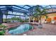 Screened pool area featuring a spa, brick-paver decking, and a tropical palm tree at 6819 Dominion Ln, Lakewood Ranch, FL 34202