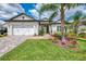 Charming home featuring a well-manicured lawn, landscaped flower beds, and a brick driveway leading to a two-car garage at 749 Tailwind Pl, Sarasota, FL 34240