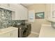 Well-organized laundry room featuring white cabinets, modern appliances, and a decorative tile backsplash at 749 Tailwind Pl, Sarasota, FL 34240