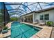 A beautiful pool and spa with a screened enclosure, surrounded by a brick patio, lounge chairs and seating area at 749 Tailwind Pl, Sarasota, FL 34240