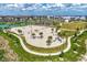 Aerial view of a sandy volleyball court surrounded by lush greenery, palm trees, and a walking path at 749 Tailwind Pl, Sarasota, FL 34240