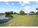 Expansive backyard with a tranquil pond view and lush green lawn, creating a serene outdoor space at 7912 Estates Dr, Sarasota, FL 34243