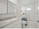 Well-lit bathroom featuring white cabinets, modern fixtures, and a tub-shower with decorative curtain at 7912 Estates Dr, Sarasota, FL 34243