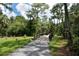 Scenic path leading to a wooden bridge amidst lush greenery and tall trees at 7912 Estates Dr, Sarasota, FL 34243
