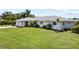 Well-maintained single-story home with a spacious front lawn, featuring a light-colored exterior and mature trees at 7912 Estates Dr, Sarasota, FL 34243