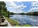 Scenic lake view surrounded by lush greenery and a clear blue sky with white clouds at 7912 Estates Dr, Sarasota, FL 34243