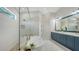 This sleek main bathroom includes a standalone tub, glass shower, and modern blue vanity with dual sinks at 8001 20Th W Pl, Bradenton, FL 34209