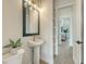Stylish powder room featuring a pedestal sink, modern lighting, and decorative mirror at 8001 20Th W Pl, Bradenton, FL 34209