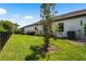Well-maintained backyard featuring lush lawn, mature landscaping, and a black metal fence under a clear, blue sky at 8229 Grande Shores Dr, Sarasota, FL 34240