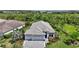 Beautiful aerial view of a home featuring a three-car garage and lovely landscaping, set against a backdrop of trees at 8229 Grande Shores Dr, Sarasota, FL 34240