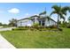 Front exterior showcasing lush landscaping, a three-car garage, and a well-maintained lawn at 8229 Grande Shores Dr, Sarasota, FL 34240