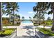 Community pool area with palm trees, lounge chairs, and cabanas on a sunny day at 8229 Grande Shores Dr, Sarasota, FL 34240