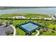 Aerial shot of well-maintained tennis and pickleball courts surrounded by trees and walking paths, set against a serene lake view at 8229 Grande Shores Dr, Sarasota, FL 34240