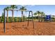 Community playground with swings and slide set amidst lush palm trees, and a protective mulch surface at 8579 Big Dipper Dr, Sarasota, FL 34241