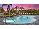 Community pool featuring lounge chairs and landscaping under a vibrant sunset sky at 8579 Big Dipper Dr, Sarasota, FL 34241