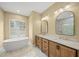 Bathroom featuring double vanity, soaking tub, and elegant mirrors and lighting at 9106 Yarberry St, Sarasota, FL 34240