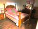 Traditional bedroom featuring a wood framed bed with ornate carvings and colorful linens, a vintage vanity, and hardwood floors at 9835 El Camino Real Ave, Port Richey, FL 34668