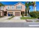 A tan townhouse with brown shutters and garage door, and a fire hydrant, palm trees, and shrubs in front at 1033 Grantham Dr, Sarasota, FL 34234