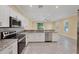 An airy kitchen with white cabinetry, granite counters, stainless steel appliances and tile floors opening to the living room at 1033 Grantham Dr, Sarasota, FL 34234