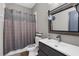 Cozy bathroom featuring a wood-look vanity, decorative mirror, and patterned shower curtain at 1116 406Th E Ct, Myakka City, FL 34251