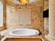 Elegant bathroom featuring a soaking tub with tile surround, a decorative inlay, and a mounted television at 11504 Splendid Ln, Tampa, FL 33626
