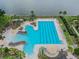 Aerial view of a luxurious community pool with lounge chairs, palm trees, and a lake at 11504 Splendid Ln, Tampa, FL 33626