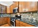 Close up of a kitchen featuring wood cabinets, mosaic backsplash, granite countertops, and stainless steel appliances at 11504 Splendid Ln, Tampa, FL 33626