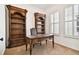 Office with built-in bookshelves, a classic desk, and bright natural light from the shuttered window at 11504 Splendid Ln, Tampa, FL 33626