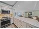 Spacious kitchen and living area with white cabinets, a modern island, and stainless steel appliances at 1212 Benjamin Franklin Dr # 306, Sarasota, FL 34236