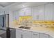 Bright kitchen with white cabinets, granite counters, a modern backsplash, and stainless appliances at 1212 Benjamin Franklin Dr # 306, Sarasota, FL 34236
