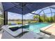 Relaxing screened in pool and hot tub with lake view, lounge chairs and a blue umbrella at 12237 Longview Lake Cir, Bradenton, FL 34211