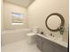 Well-lit bathroom with a modern vanity, round mirror, bathtub, and a view from the window at 12541 Estrella Blvd, Punta Gorda, FL 33955